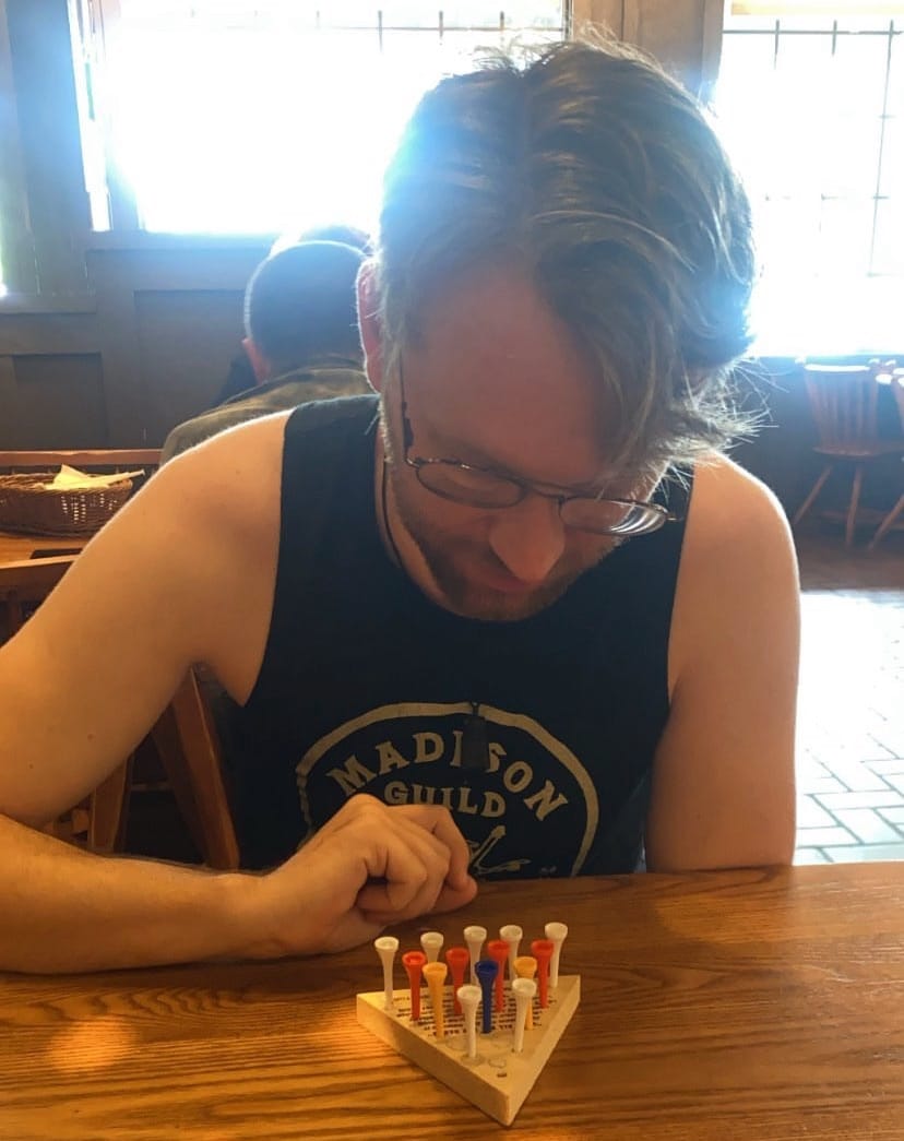 George Jackson plays a peg game at a wooden table
