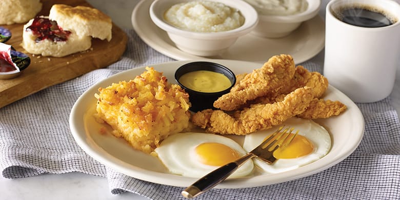 A plate with eggs, hash brown casserole, and chicken tenders