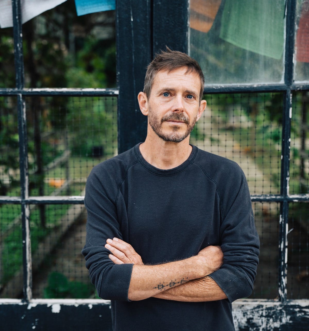 Glen Phillips with arms crossed in front of a window