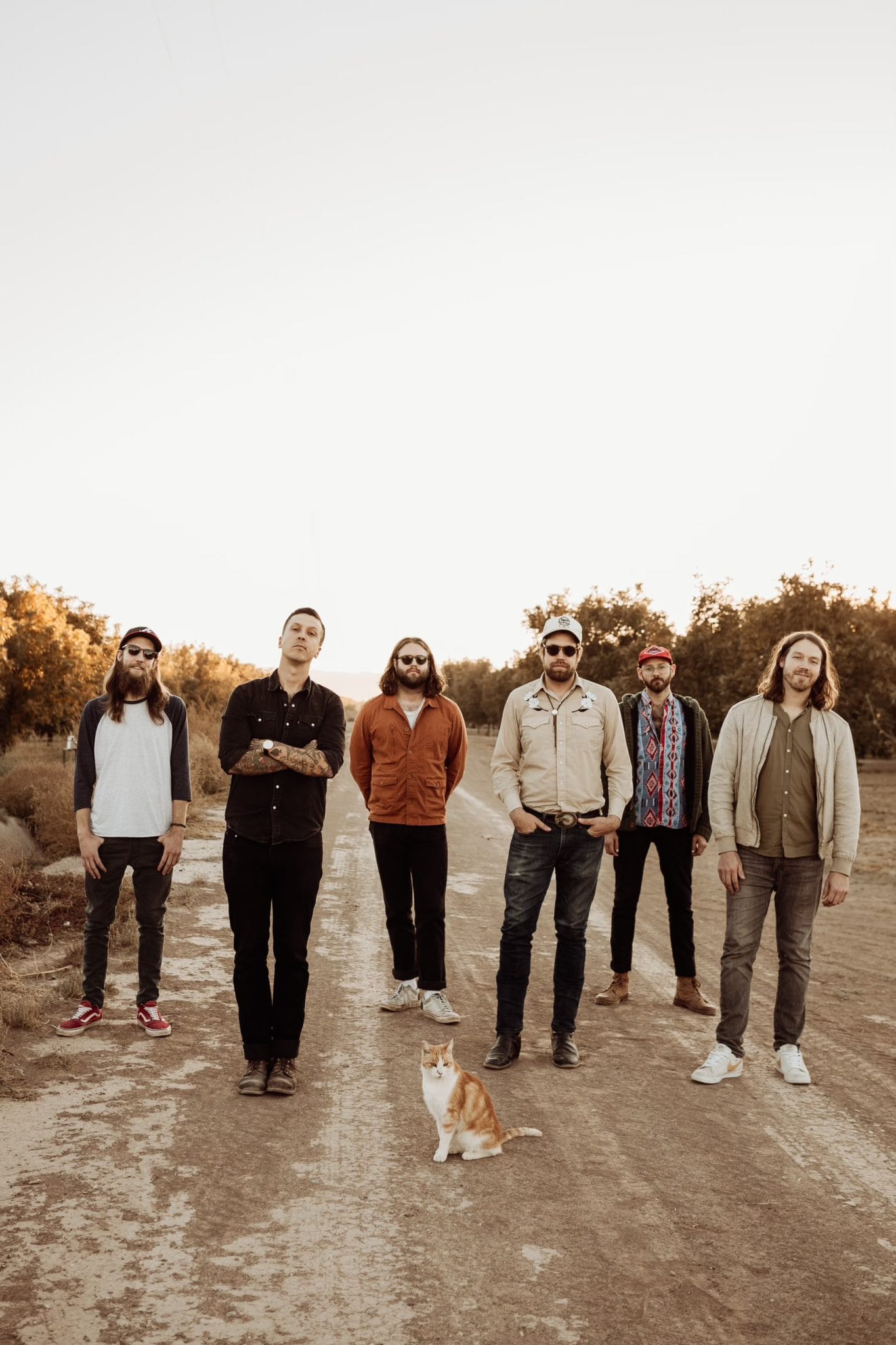 The six members of American Aquarium on a dirt road, plus a cat