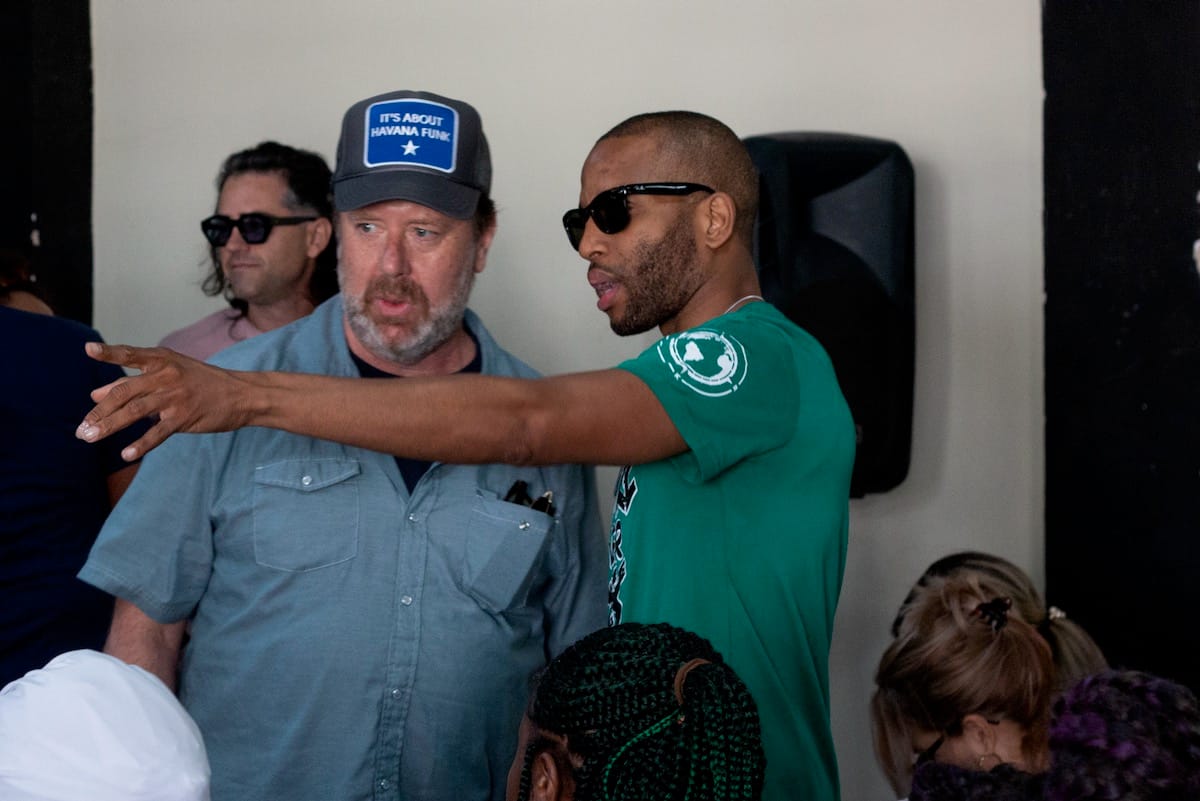 Trombone Shorty points to his right across Bill Taylor