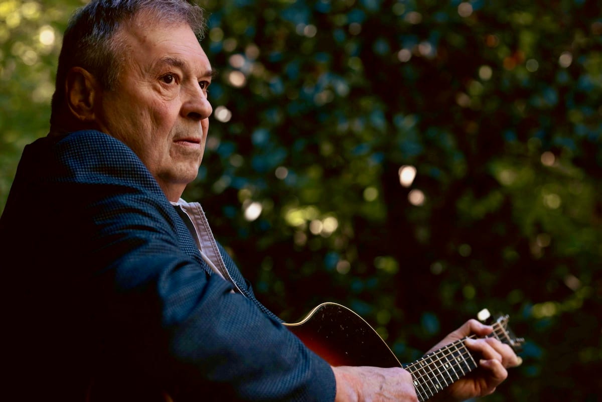 Side view of David Childers playing an acoustic guitar