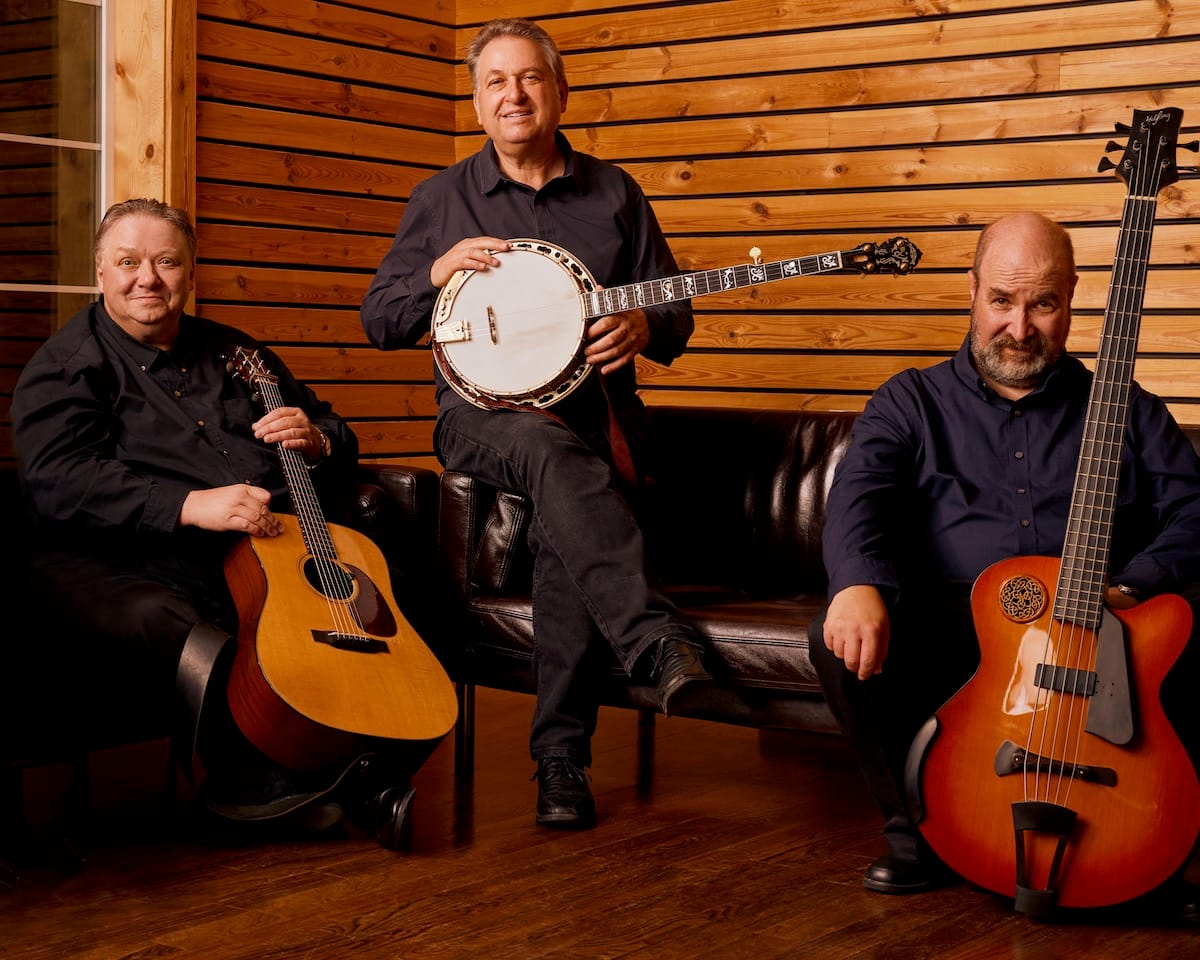 The three members of the Kruger Brothers in a wood paneled room