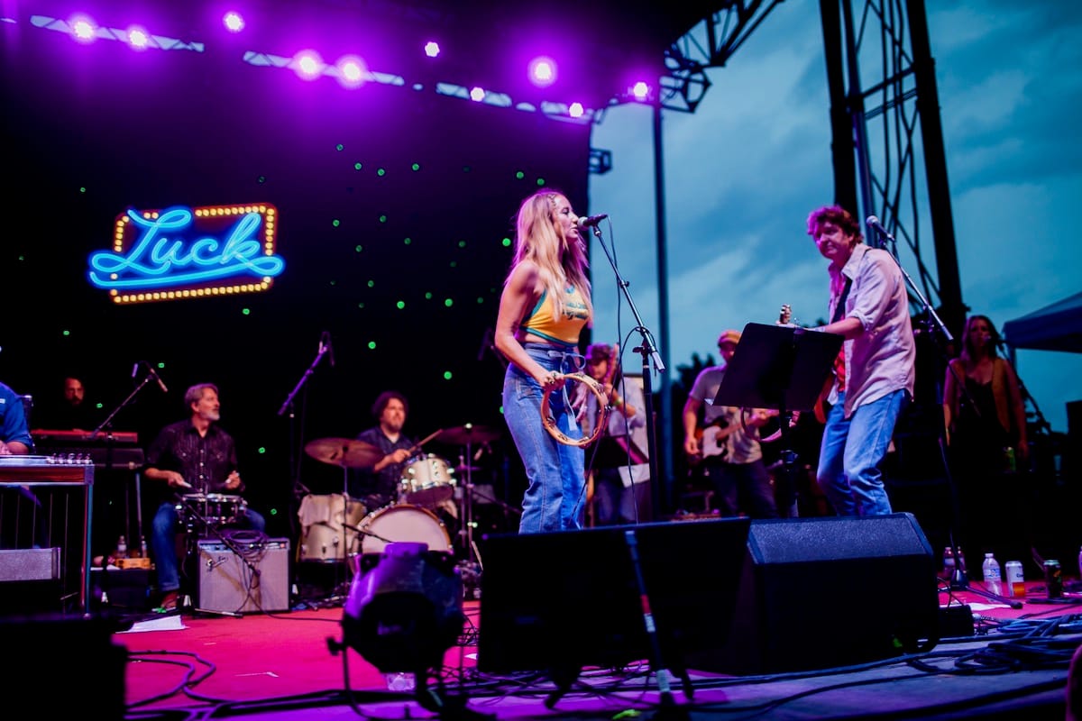 Margo Price and Bruce Robison on stage with neon Luck sign in the background