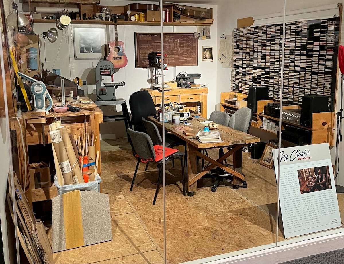 A small room with a wood table and shelves and a collection of tapes on one wall.