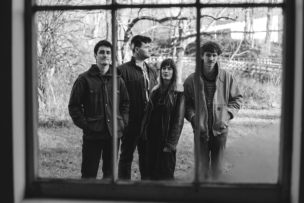 The four members of The Felice Brothers as seen through a paned window